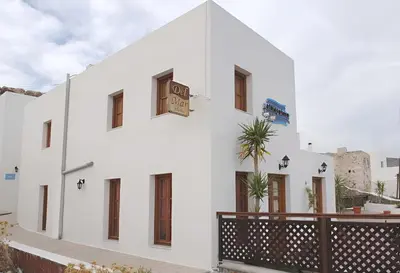 a white building with a clock on the side of it at Lindos Del Mar Suites - Adults Only in Líndos