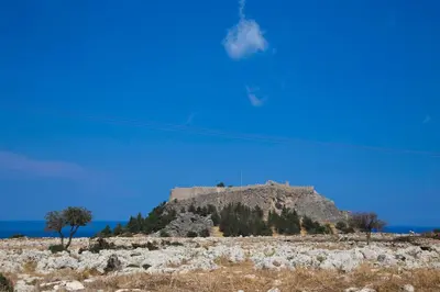 a castle on top of a hill with the ocean at Lindos Portes Suites - Adults Only in Líndos