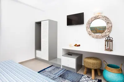 a bedroom with a bed and a desk and a mirror at Lindos Portes Suites - Adults Only in Líndos