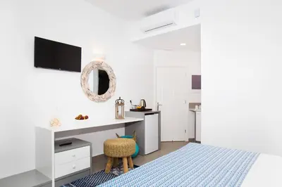 a white bedroom with a bed and a sink at Lindos Portes Suites - Adults Only in Líndos