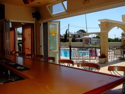 a dining room with a table and chairs and a pool at Antonios Hotel in Faliraki