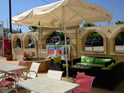 a patio with tables and chairs and an umbrella at Antonios Hotel in Faliraki