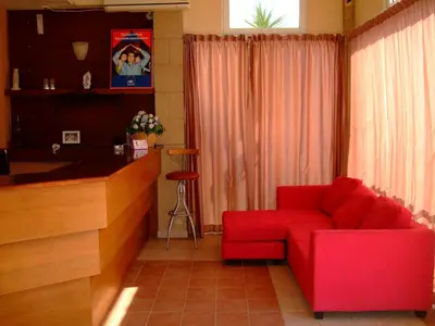 a living room with a red couch and a bar at Antonios Hotel in Faliraki