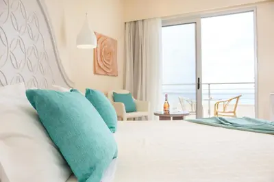 a bedroom with a bed with blue pillows at Pegasos Deluxe Beach Hotel in Faliraki
