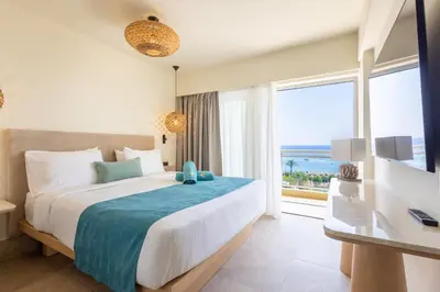 a bedroom with a large bed and a large window at Pegasos Deluxe Beach Hotel in Faliraki