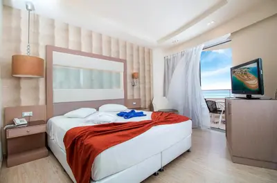 a bedroom with a large bed and a television at Pegasos Deluxe Beach Hotel in Faliraki