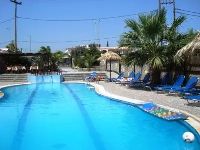 a large blue swimming pool with chairs and palm trees at SunnySun Studios in Faliraki