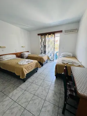 a hotel room with two beds and a table and a window at SunnySun Studios in Faliraki
