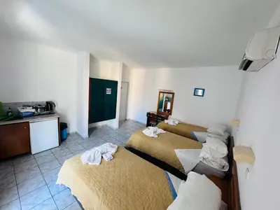 a hotel room with three beds and a kitchen at SunnySun Studios in Faliraki