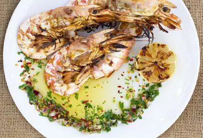 a plate of food with shrimp and a lemon at Tsambikos Apts in Faliraki