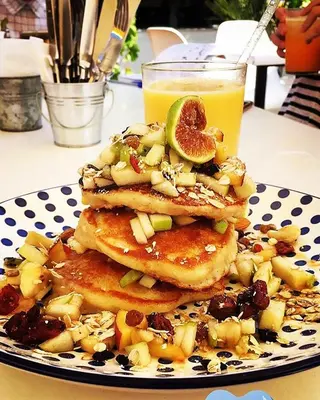 a stack of pancakes with fruit and a glass of orange juice at Tsambikos Apts in Faliraki