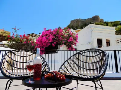 two chairs and a glass of wine on a table at Lindos Aktaia Villa in Líndos