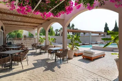 an outdoor patio with tables and chairs and flowers at Kolymbia Bay Art Boutique Hotel - Adults Only in Kolimbia