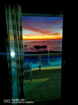 a view of the ocean from a window with a sunset at Tsampika's Sea View Home in Archangelos
