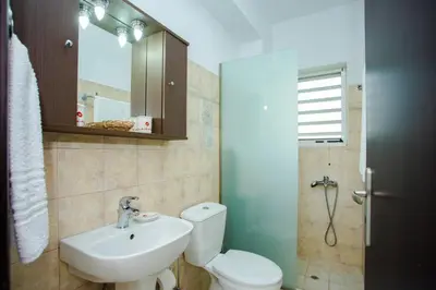 a bathroom with a white toilet and a sink at Tsampika's Sea View Home in Archangelos