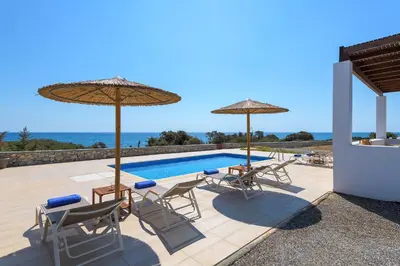 a patio with chairs and umbrellas and a swimming pool at Villa Corinna in Lachania