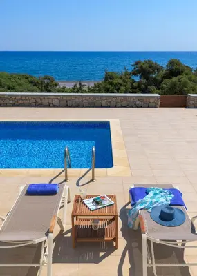 a swimming pool with two chairs and a table next to a pool at Villa Corinna in Lachania