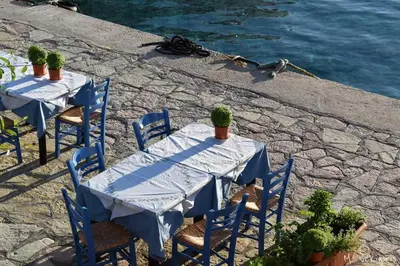 two blue tables and chairs with plants on a stone patio at House Galini in Halki