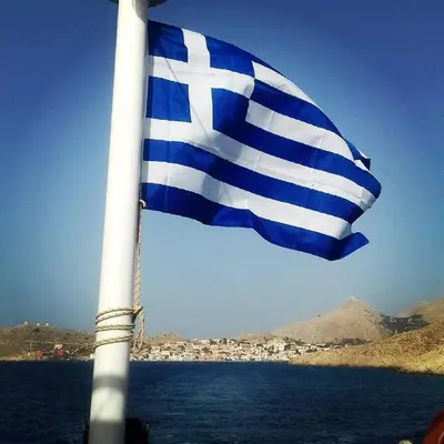 a blue and white flag on a boat in the water at House Galini in Halki