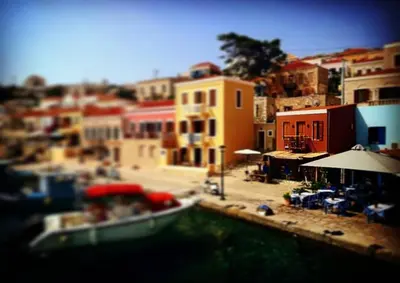 a boat in the water next to a city at House Galini in Halki