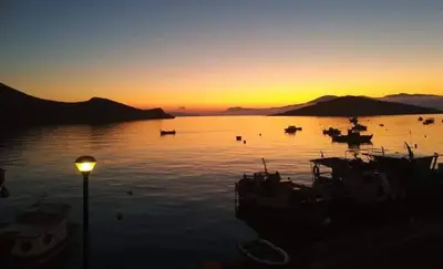a group of boats in the water at sunset at House Galini in Halki