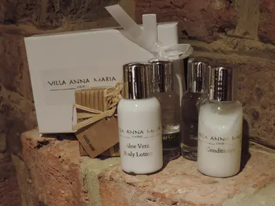 three bottles of soap and a box on a stone shelf at Villa Anna Maria Lindos in Líndos