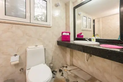 a bathroom with a toilet and two sinks at Elefteria Apts & Suites in Kolimbia