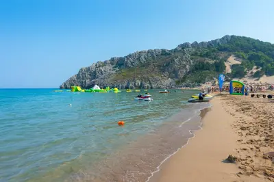 a beach with a group of people in the water at Elefteria Apts & Suites in Kolimbia