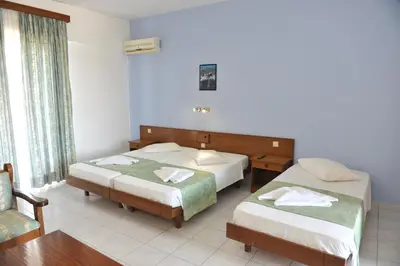 a hotel room with two beds and a chair at Maritime in Kremasti