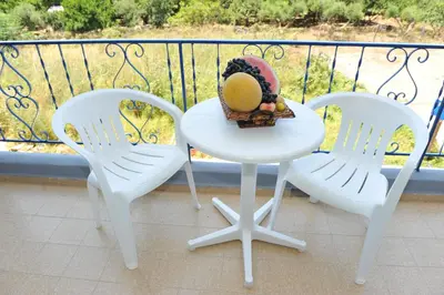 two chairs and a table with a basket of fruit on a balcony at Maritime in Kremasti
