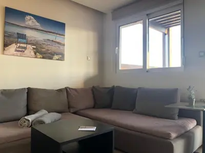 a living room with a brown couch and two windows at MV83 new marina in Rhodes Town