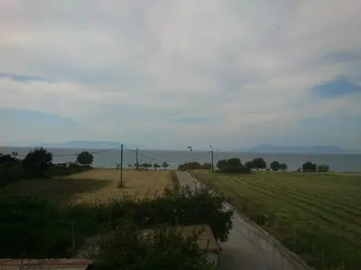 a field with a kite flying over the water at Kitesurf Paradise Studios in Theologos