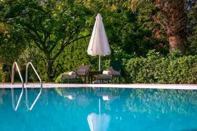 an umbrella and two chairs and a table and a pool at Royal Classico Villa in Kolimbia