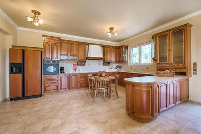 a large kitchen with wooden cabinets and a table at Royal Classico Villa in Kolimbia