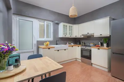 a kitchen with white cabinets and a wooden table at Melita City Apartment in Rhodes Town