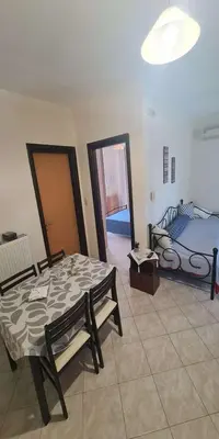 a room with two beds and a table and chairs at Retas apartment in Kremasti