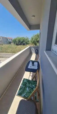 a balcony with two chairs and a table and a window at Retas apartment in Kremasti