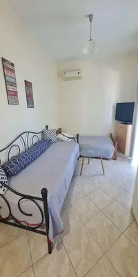 a bedroom with a bed and a couch and a tv at Retas apartment in Kremasti
