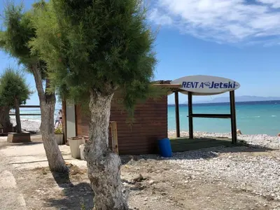a sign on a beach next to two trees at Retas apartment in Kremasti