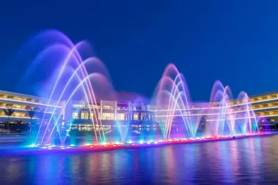 a fountain in the water in front of a building at Princess Andriana Resort & Spa - Ultra All-Inclusive in Kiotari