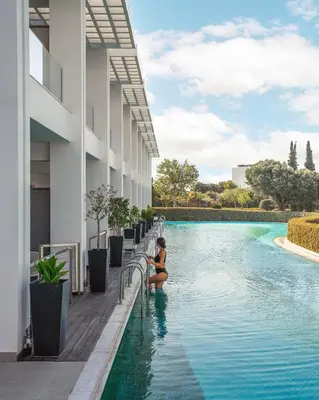 a woman sitting in a swimming pool next to a building at Princess Andriana Resort & Spa - Ultra All-Inclusive in Kiotari