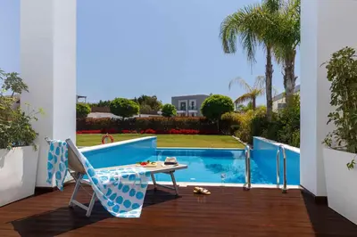 a patio with a table and chairs next to a swimming pool at Princess Andriana Resort & Spa - Ultra All-Inclusive in Kiotari