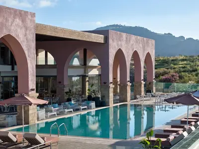 a hotel with a swimming pool with chairs and umbrellas at Boutique 5 Hotel & Spa - Adults Only in Kiotari