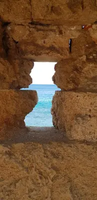a view of the ocean through a rock cave at Aramis Boutique House in Rhodes Town