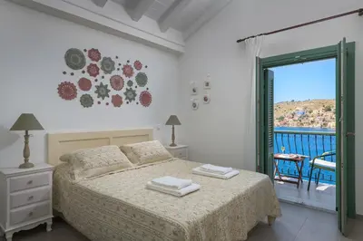 a white bedroom with a bed and a balcony at Aegli Villa by Blue Wave in Symi