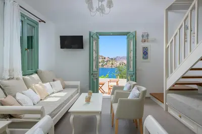 a living room with a couch and chairs and a window at Aegli Villa by Blue Wave in Symi