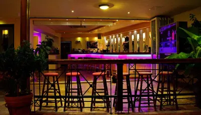 a bar with stools in a room with purple lights at Kalathos Sun Hotel in Kalathos