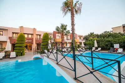 a pool at a resort with a palm tree and chairs at Stavros Melathron Studios in Kallithea Rhodes