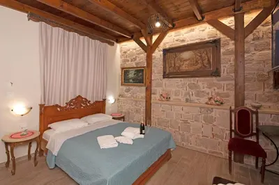 a bedroom with a bed and a stone wall at Arionos Rooms - Old Town in Rhodes Town