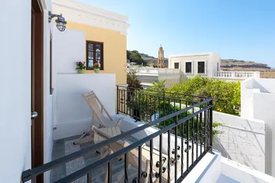 a balcony of a house with a chair at Lindos Heart Apartments in Líndos